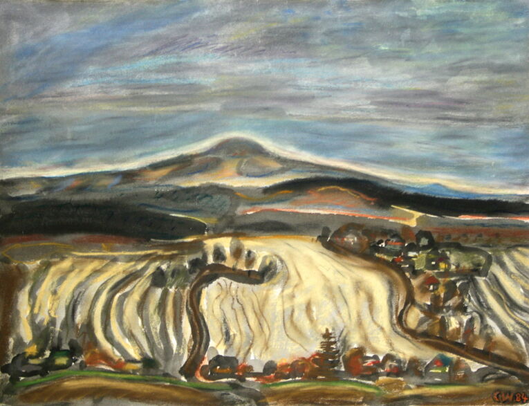 im Mittelpunkt markante Bergkuppe des Haßberges, davor dunkle Wälder und Bergrücken, Felder und Wege, im Vordergrund am unteren Bildrand kleine Häuser und Bäume eines Dorfes, der Himmel blau-grau und wolkenverhangen